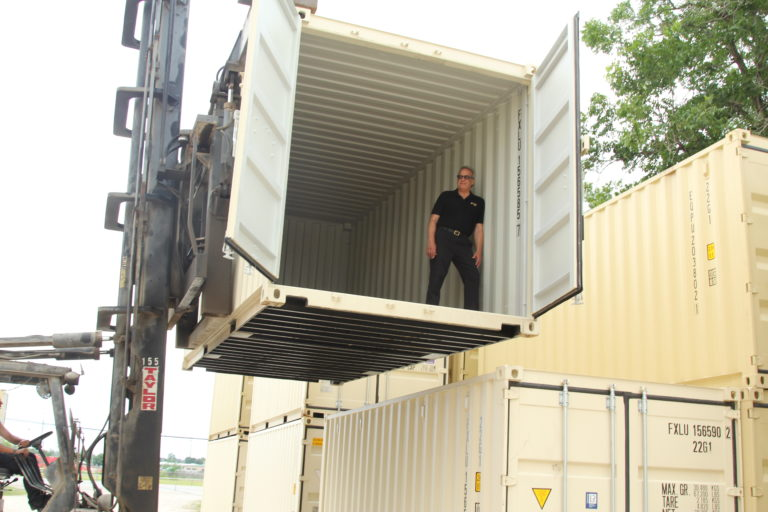 Steve McVille standing inside a shipping container lifted by a forklift